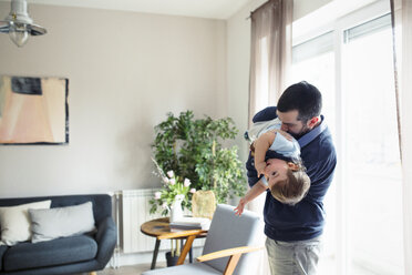 Verspielter Mann trägt seinen Sohn durch das Fenster zu Hause - CAVF44471