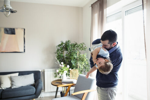 Verspielter Mann trägt seinen Sohn durch das Fenster zu Hause - CAVF44471