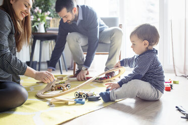Parents assisting son in making toy railroad track at home - CAVF44480