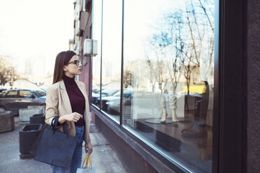 Frau schaut beim Einkaufen in der Stadt in ein Schaufenster - CAVF44498
