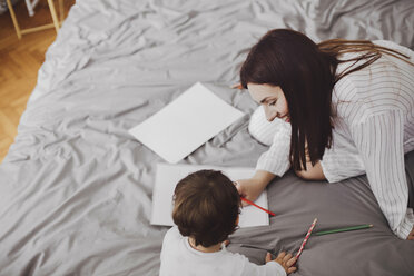 Hohe Winkel Ansicht der glücklichen Mutter und Baby Junge mit Schulmaterial auf dem Bett zu Hause - CAVF44524
