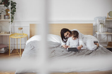 Glückliche Mutter mit Tablet-Computer mit Baby-Junge auf dem Bett zu Hause - CAVF44526