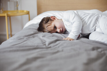 Portrait of cute baby boy lying in bed at home - CAVF44529