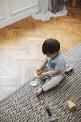 Hohe Winkel Ansicht von Baby-Junge spielt mit Spielzeug Teetasse und Untertasse auf Teppich zu Hause - CAVF44542