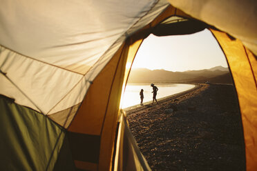 Friends at lakeshore seen through tent - CAVF44581