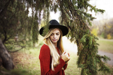 Beautiful woman standing by branches on field - CAVF44636