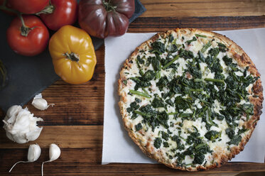 Hohe Winkelansicht von Pizza und Gemüse auf Holztisch - CAVF44641