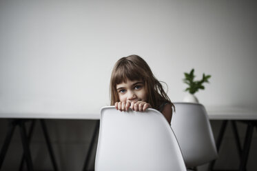 Portrait of cute girl sitting on chair at home - CAVF44664