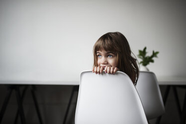 Thoughtful girl sitting on chair at home - CAVF44665