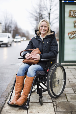 Portrait of happy disabled woman in wheelchair smiling outdoors stock photo