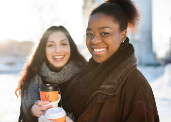 Portrait of happy female friends in warm clothes holding disposable cups - MASF06107