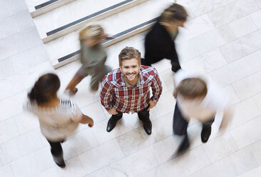 Portrait of happy young businessman surrounded with colleagues - MASF06111