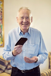 Porträt eines glücklichen älteren Mannes, der seine Brieftasche hält, während er zu Hause steht - MASF06113