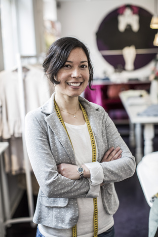 Portrait of happy female fashion designer standing arms crossed in studio stock photo