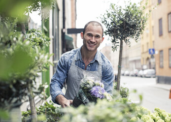 Porträt eines glücklichen männlichen Blumenhändlers, der vor einem Blumenladen arbeitet - MASF06124