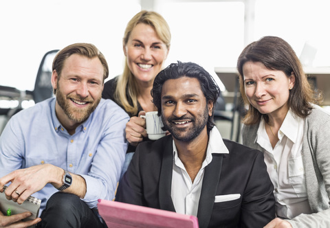 Porträt von glücklichen multiethnischen Geschäftsleuten, die im Büro zusammensitzen, lizenzfreies Stockfoto