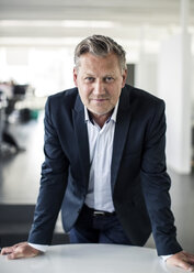 Portrait of mature businessman leaning on desk in office - MASF06142