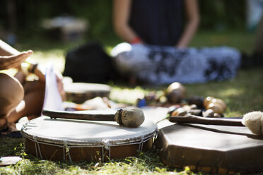 Drums and drumsticks on grassy field at park - CAVF44738