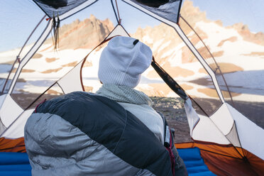 Rückansicht eines Wanderers, der im Zelt sitzend die Aussicht betrachtet - CAVF44798