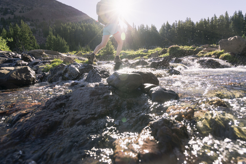 Niedriger Ausschnitt einer Wanderin, die auf Felsen am Blue River läuft, lizenzfreies Stockfoto