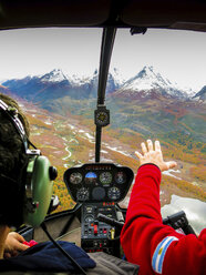 Ausgeschnittenes Bild eines Mannes mit Pilot im Hubschrauber, der über die Landschaft fliegt - CAVF44817