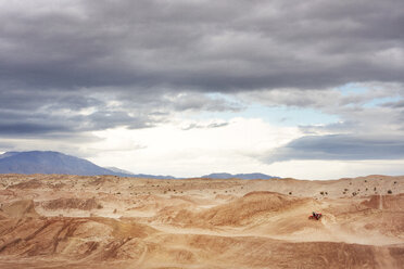 Entfernte Ansicht einer Person auf einem Motorrad in der Wüste - CAVF44902