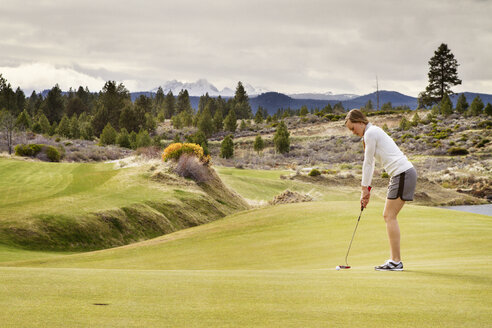 Seitenansicht einer Frau, die auf einem Feld Golf spielt - CAVF44928