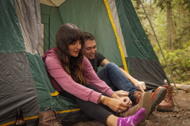 Couple tying shoelace while sitting in tent - CAVF44980