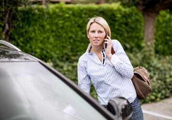 Mittlere erwachsene Frau benutzt Mobiltelefon im Auto - MASF06155