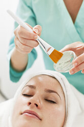 Midsection of a beautician applying cream with make-up brush to young woman - MASF06162