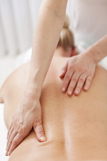 Ältere Therapeutin gibt Rückenmassage an mittelgroße Frau im Wellnessbereich - MASF06211
