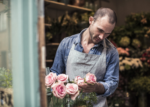 Mittlerer Erwachsener, männlicher Florist, der Blumen im Geschäft analysiert, lizenzfreies Stockfoto