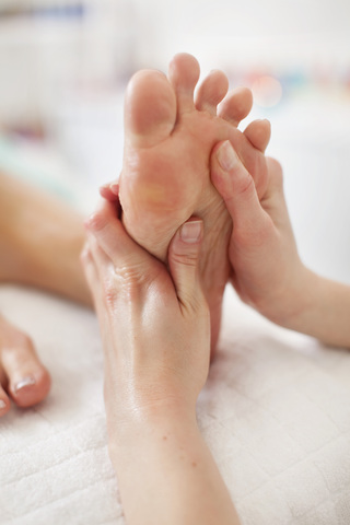 Menschliche Hand massiert Fußsohle im Wellnessbereich, lizenzfreies Stockfoto