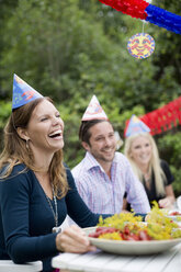Glückliche junge Frau mit Freunden am Esstisch, die eine Flusskrebs-Party feiern - MASF06277
