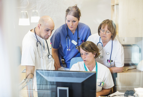 Male and female doctors using computer together in clinic stock photo