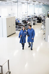 High angle view of male and female engineers discussing while walking in factory - MASF06333