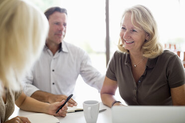 Happy woman with colleagues sitting at business meeting - MASF06348