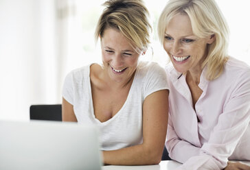 Happy businesswomen using laptop at desk in office - MASF06349