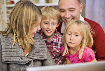 Glückliche vierköpfige Familie mit Laptop zu Hause - MASF06377