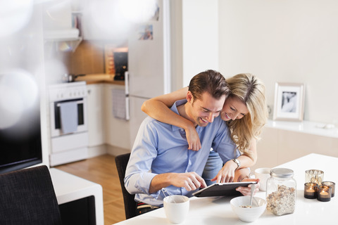 Glückliches Paar benutzt digitales Tablet am Frühstückstisch, lizenzfreies Stockfoto