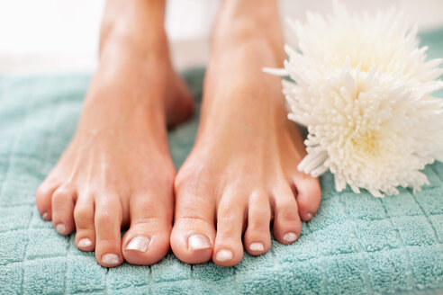 Nahaufnahme der Füße einer Frau auf einem Handtuch im Wellnessbereich - MASF06401