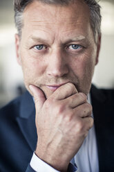 Close-up portrait of serious mature businessman with hand on chin - MASF06415