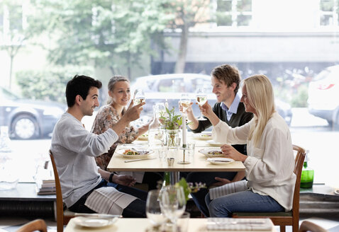 Gruppe von Freunden stößt mit Weingläsern am Restauranttisch an - MASF06426