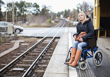 Disabled woman in wheelchair waiting for the train at railway station - MASF06443