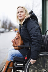Behinderte Frau im Rollstuhl schaut im Freien weg - MASF06444