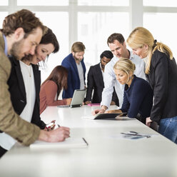 Gruppe von Geschäftsleuten, die gemeinsam an einem Schreibtisch im Büro arbeiten - MASF06463