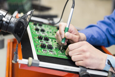 Cropped image of electrician's hand soldering circuit board - MASF06467