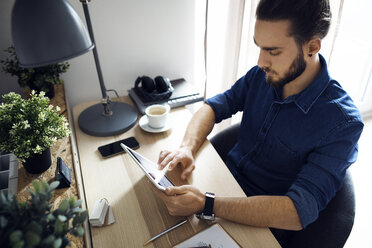 High angle view of man using tablet computer while sitting at table - CAVF45011