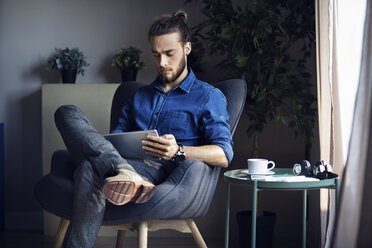 Man using tablet computer while sitting on chair at home - CAVF45014