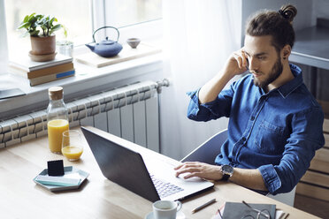 High angle view of man talking on mobile phone while sitting at table - CAVF45024